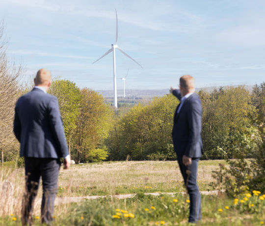 Energiselskaber vil gerne opkøbe landbrugsjord for at opføre solpaneler og vindmøller, ofte som optionsaftaler. EDC mæglere står og peger på vindmøller i horisonten.